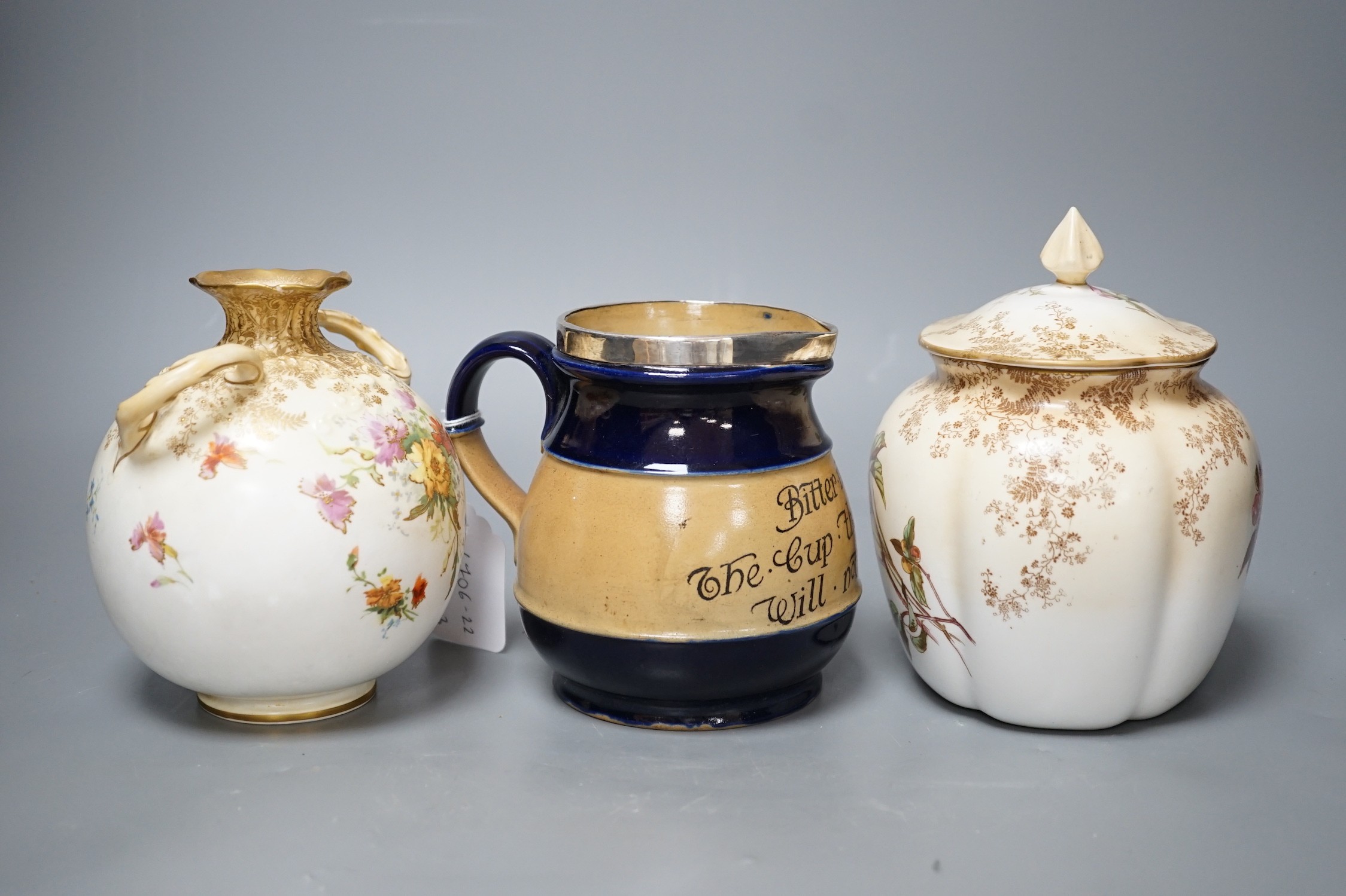 A late 19th / Early 20th century Doulton two handled vase and a Doulton vase and cover both painted with flowers on a blush ivory ground, Doulton Burslem England mark together with a Royal Doulton jug with silver mount a
